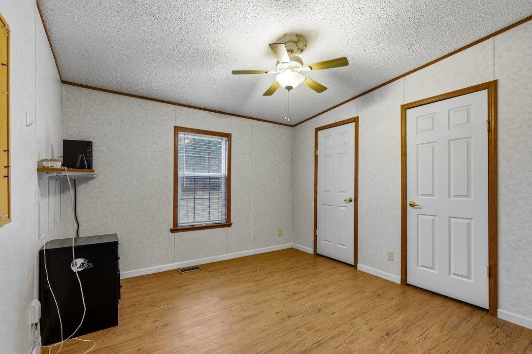 181 EV Road Loris, SC 29569 - Photo 20 of 33 Unfurnished bedroom with light wood finished floors, crown molding, a ceiling fan, and a textured ceiling