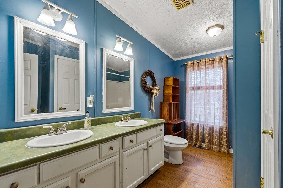 181 EV Road Loris, SC 29569 - Photo 21 of 33 Bathroom with crown molding, a textured ceiling, double vanity, dark wood-type flooring, and curtained shower
