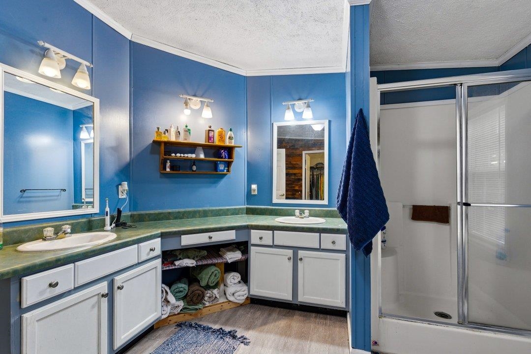 181 EV Road Loris, SC 29569 - Photo 27 of 33 Full bathroom featuring ornamental molding, a textured ceiling, a shower stall, double vanity, and light wood-type flooring