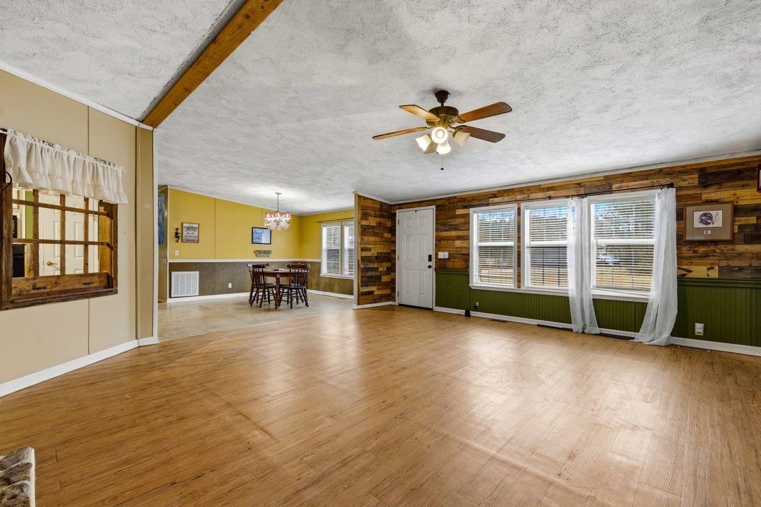 181 EV Road Loris, SC 29569 - Photo 9 of 33 Unfurnished living room featuring a textured ceiling, wood finished floors, wooden walls, a chandelier, and ceiling fan