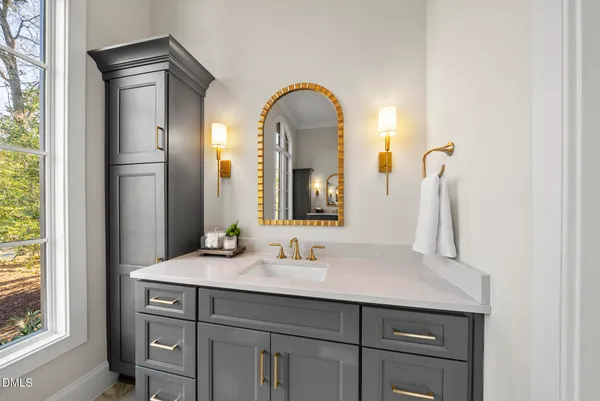 a bathroom with a granite countertop sink toilet a large mirror a shower and a window
