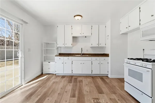 a kitchen with granite countertop white cabinets and white appliances