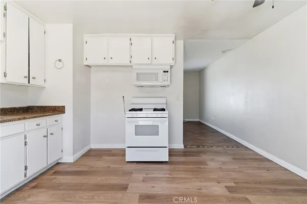 a kitchen with granite countertop white cabinets and white appliances