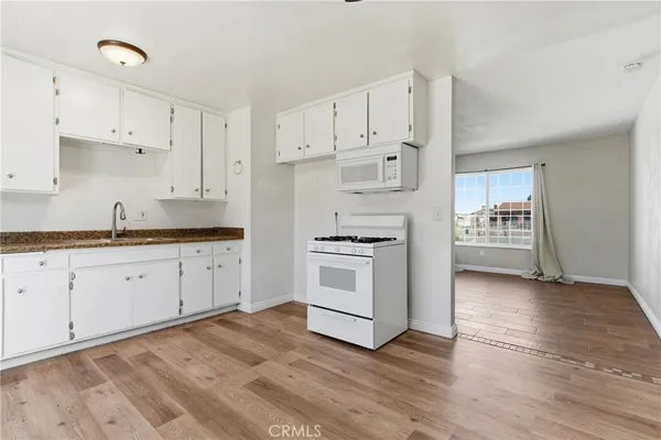 a kitchen with granite countertop white cabinets and white appliances