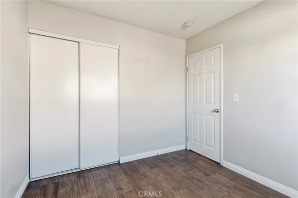 a view of an empty room with wooden floor and closet