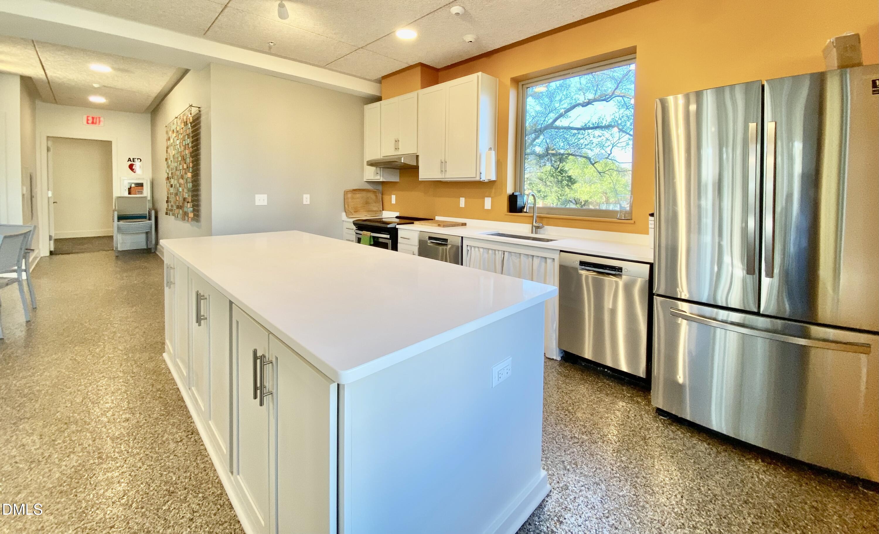 610 Trent Drive, Unit 403 Durham, NC 27705 - Photo 34 of 51 a kitchen with a refrigerator a stove a sink dishwasher and a dining table with wooden floor