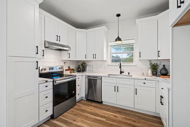 a kitchen with stainless steel appliances granite countertop a sink a stove and cabinets with wooden floor