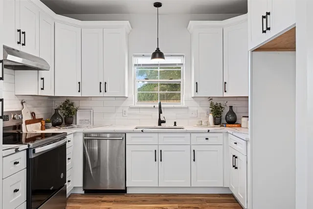a kitchen with white cabinets stainless steel appliances and sink