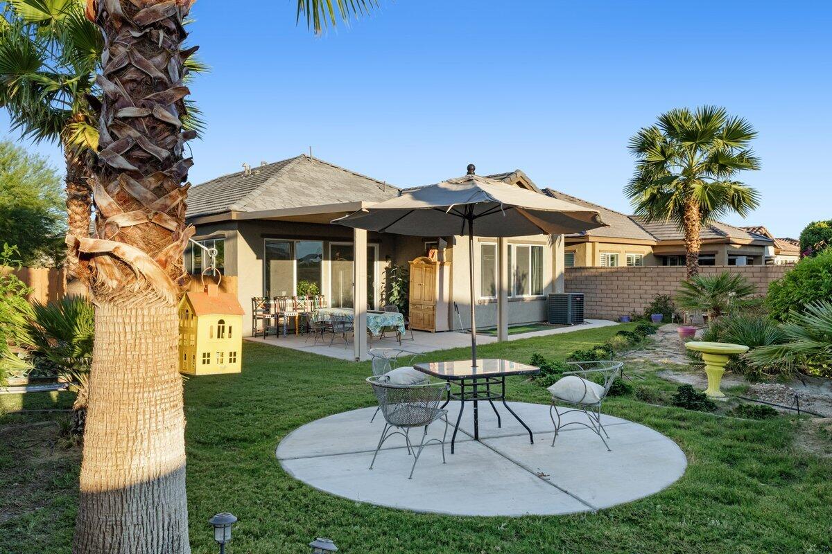44027 Triolo Way Indio, CA 92203 - Photo 14 of 17 a patio with a table and chairs and potted plants with large tree