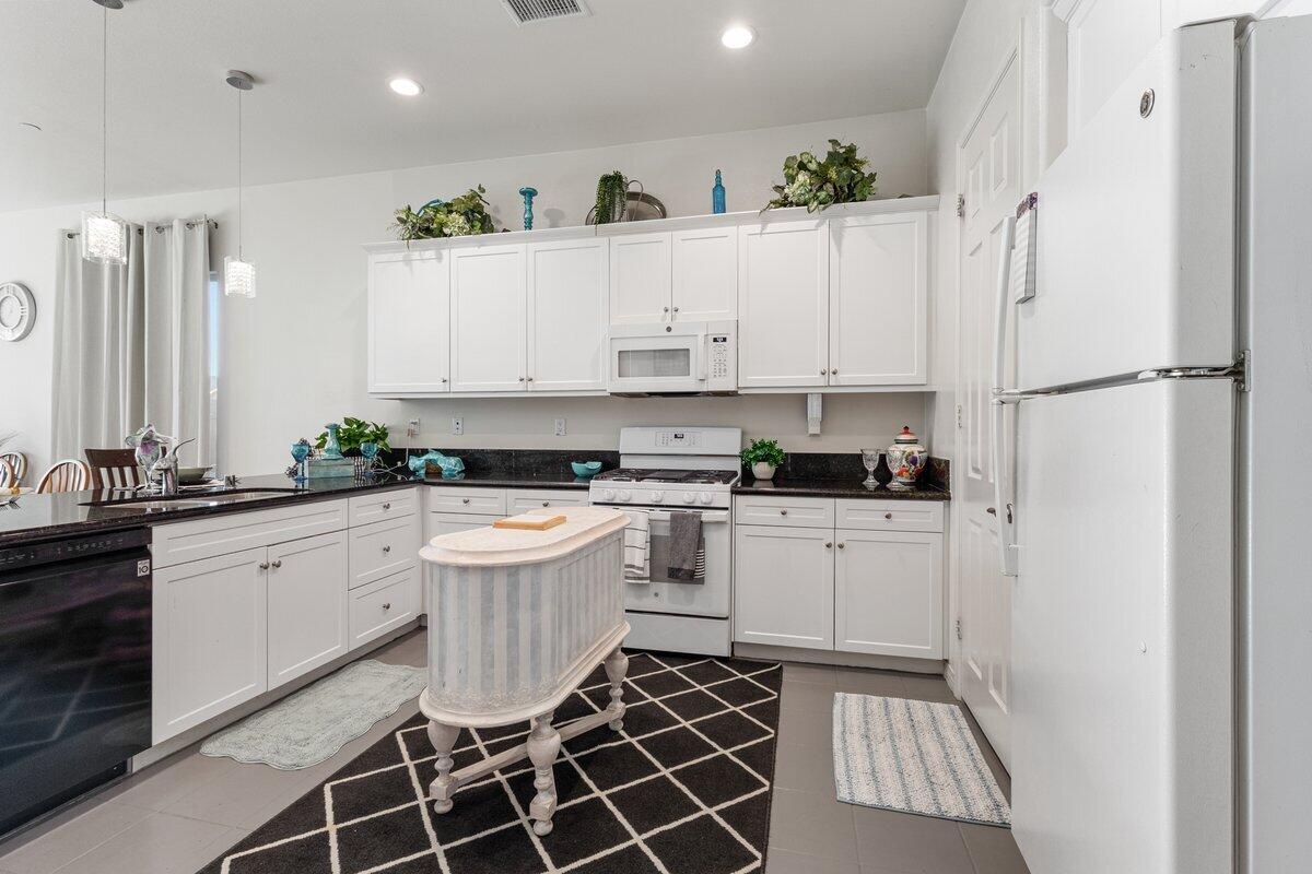 44027 Triolo Way Indio, CA 92203 - Photo 5 of 17 a kitchen with white cabinets and white appliances