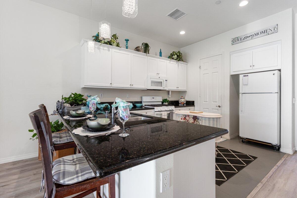 44027 Triolo Way Indio, CA 92203 - Photo 6 of 17 a kitchen with granite countertop a table chairs stove and refrigerator