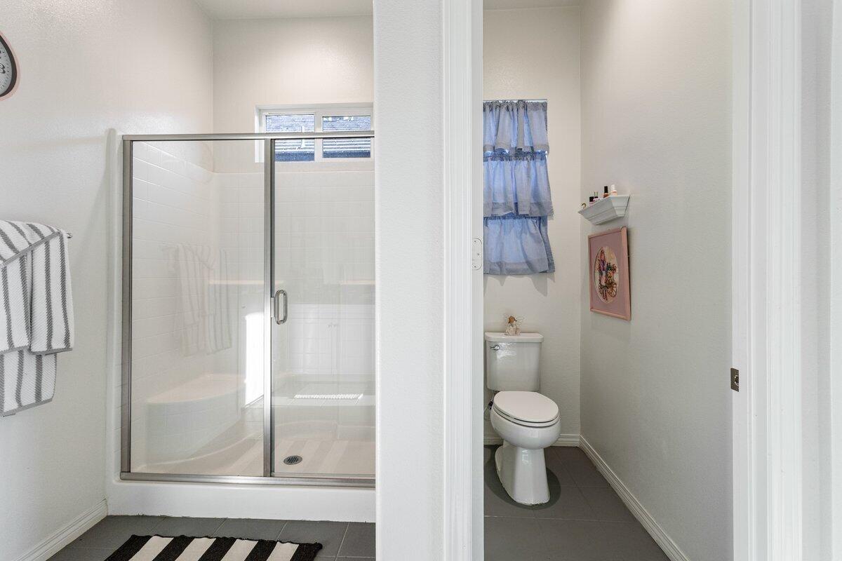 44027 Triolo Way Indio, CA 92203 - Photo 10 of 17 a bathroom with a granite countertop shower and a toilet