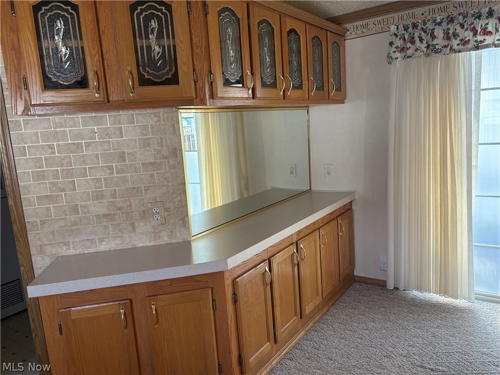 4455 Cleveland Road, Unit 20 Wooster, OH 44691 - Photo 16 of 38 Kitchen featuring glass fronted cabinets, wood finish cabinets, light countertops, light colored carpet, and glass doors to covered deck