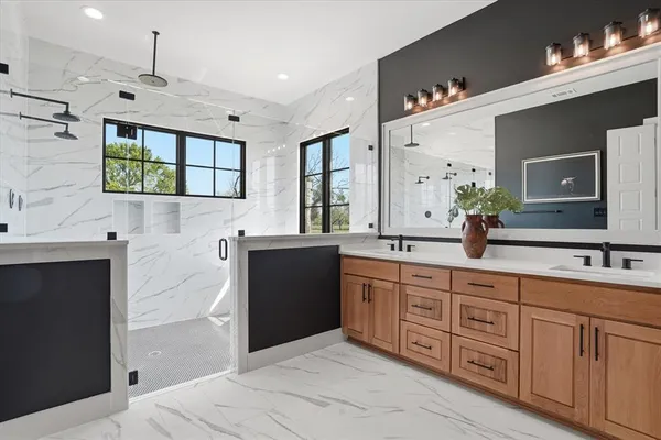 a spacious bathroom with a double vanity sink a mirror a bathtub and a shower