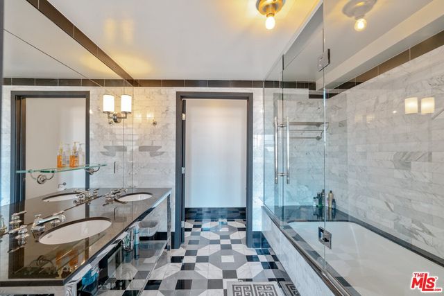 a bathroom with a granite countertop sink a mirror a bathtub and shower