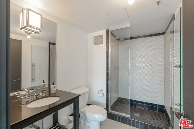 a bathroom with a granite countertop sink toilet a mirror and shower