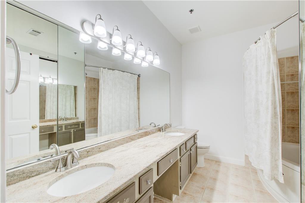 2865 Lenox Road Northeast, Unit 102 Atlanta, GA 30324 - Photo 24 of 35 a bathroom with a granite countertop sink a large mirror and a shower