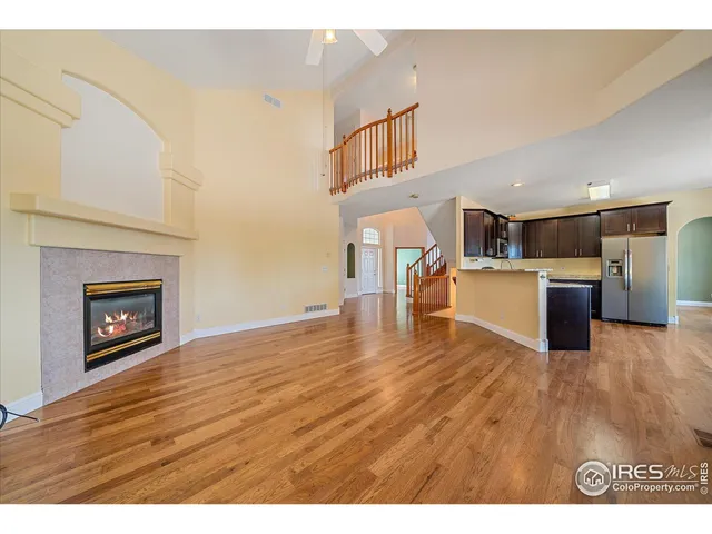 a view of kitchen and empty room with wooden floor