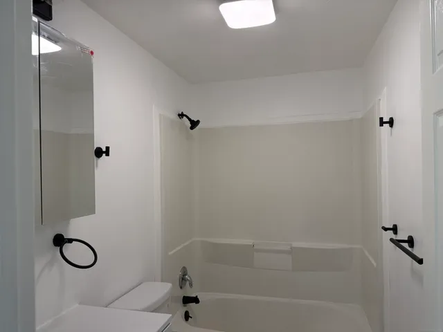 a bathroom with a granite countertop toilet a sink and shower