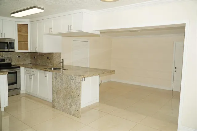a kitchen with granite countertop a sink and white cabinets
