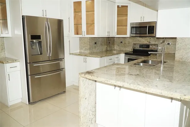 a kitchen with granite countertop a refrigerator and a sink