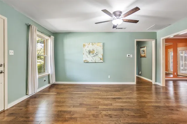 a view of an empty room with window and a chandelier fan