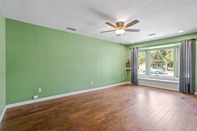 a view of an empty room with window and chandelier fan