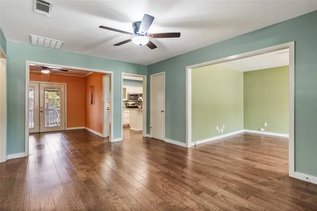 an empty room with wooden floor and a ceiling fan
