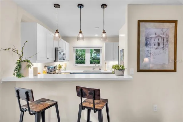 a kitchen with stainless steel appliances a dining table chairs and white cabinets