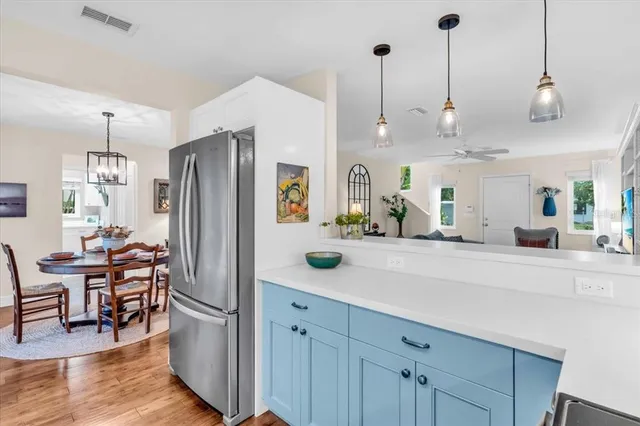 a kitchen with stainless steel appliances kitchen island granite countertop a refrigerator a stove a dining table and chairs with wooden floor