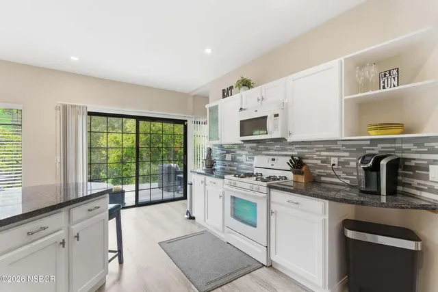 a kitchen with stainless steel appliances granite countertop a stove a sink and a microwave