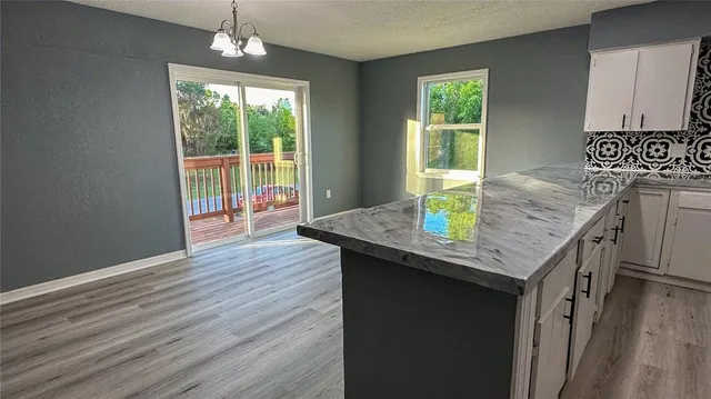 a kitchen with granite countertop a table chairs in it and wooden floors