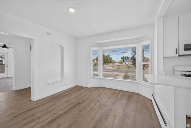 220 East Greenwood Avenue Midvale, UT 84047 - Photo 12 of 46 Bright dining area featuring a prominent bay window, recessed ceiling lighting, wood-finish flooring, a built-in wall niche, and white cabinetry with a matching countertop
