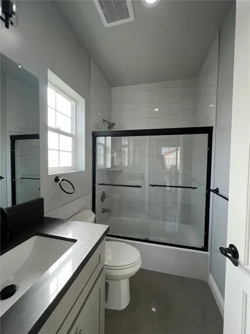a bathroom with a granite countertop sink toilet a mirror and shower