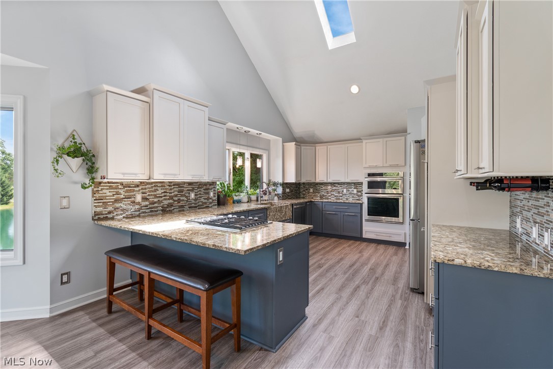 7300 Branch Road Medina, OH 44256 - Photo 13 of 34 Kitchen with decorative backsplash, a breakfast bar, light hardwood / wood-style flooring, and a skylight