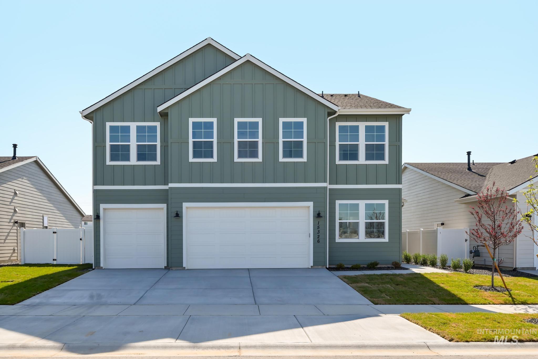 View of front of property with board and batten siding, a gate, a garage, and driveway