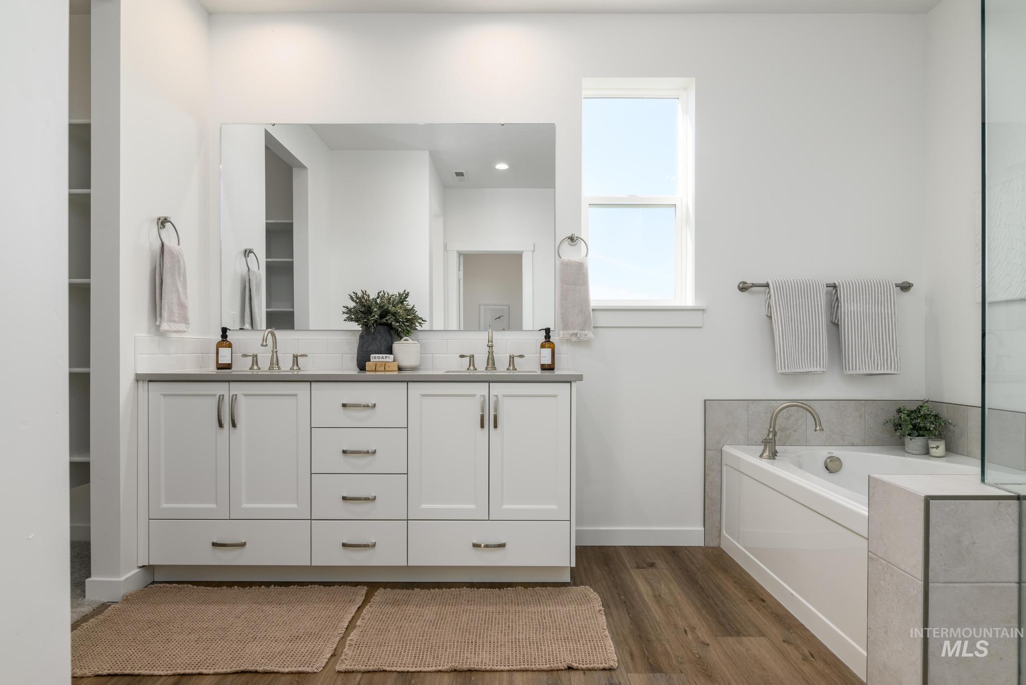 855 West Bay Street Middleton, ID 83644 - Photo 12 of 13 Full bath with double vanity, a garden tub, dark wood-type flooring, and backsplash