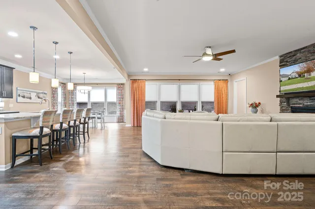 a view of a kitchen with kitchen island stainless steel appliances wooden floor and a large window