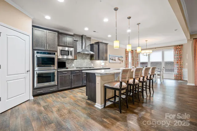 a kitchen with stainless steel appliances kitchen island granite countertop a table chairs sink and cabinets