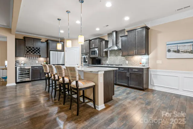 a kitchen with stainless steel appliances granite countertop a stove a sink a oven a dining table and chairs with wooden floor