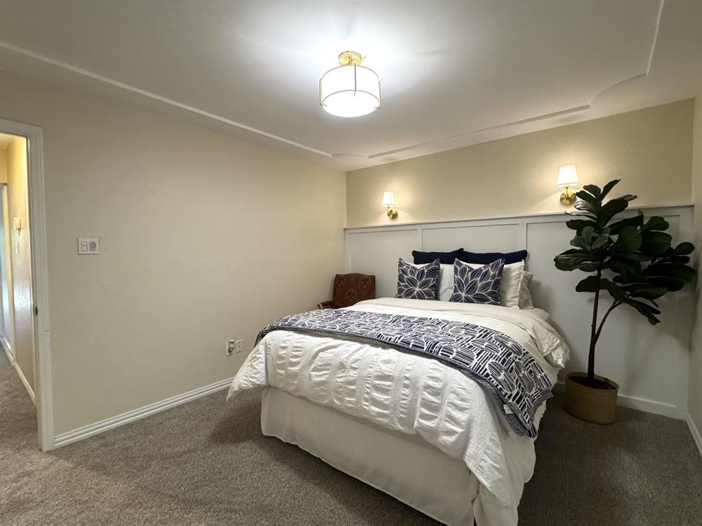 113 Northeast Timber Ridge Drive Burleson, TX 76028 - Photo 29 of 36 Bedroom 2 features carpeting, a decorative wainscoting accent wall with two mounted sconces, a ceiling light fixture, and crown molding