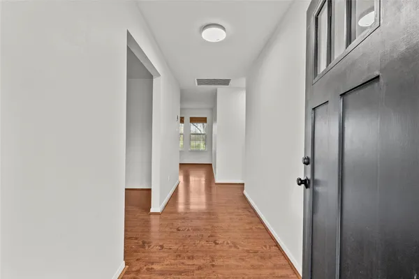 an empty room with wooden floor chandelier fan and windows
