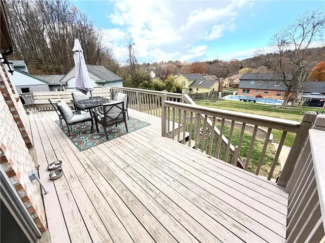 a view of a roof deck with table and chairs a barbeque with wooden floor and fence