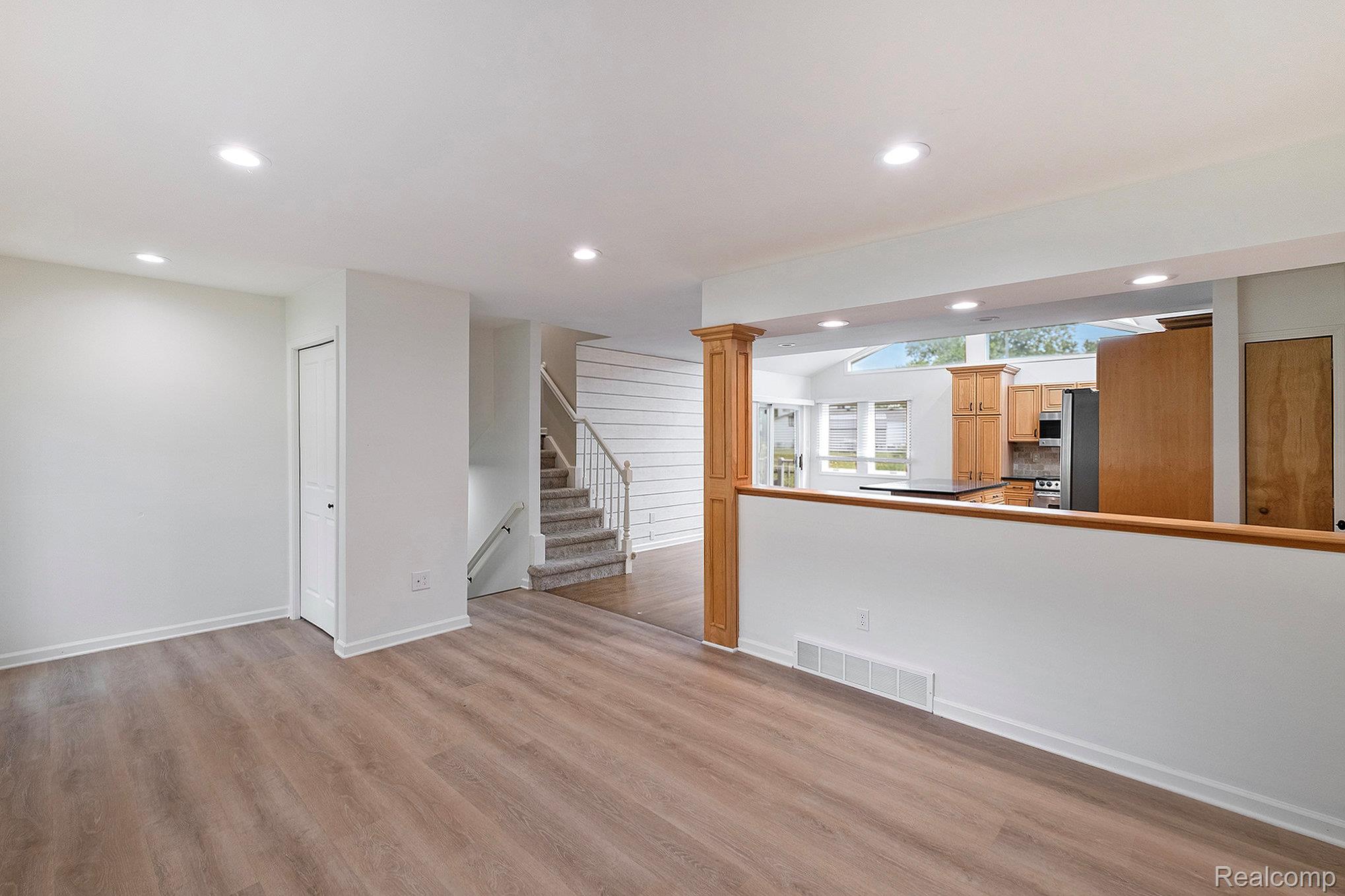 12147 Torrey Road Fenton, MI 48430 - Photo 2 of 19 Unfurnished living room featuring recessed lighting, light wood-style floors, stairway, and decorative columns