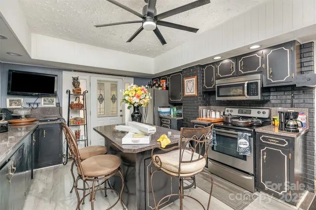a kitchen with stainless steel appliances a stove a sink dishwasher a dining table and chairs with wooden floor