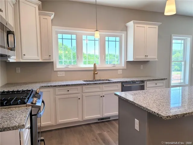 a kitchen with granite countertop a sink a stove and cabinets