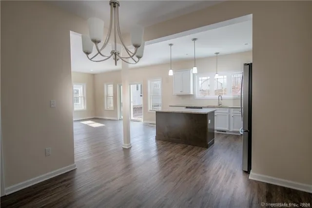 a view of a kitchen and an empty room with wooden floor