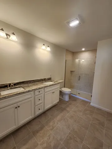a bathroom with a granite countertop sink a toilet and a mirror