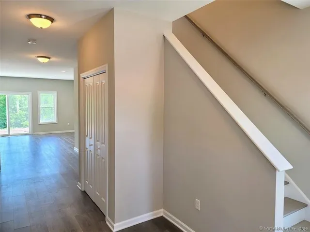 a view of a hallway with wooden floor and closet