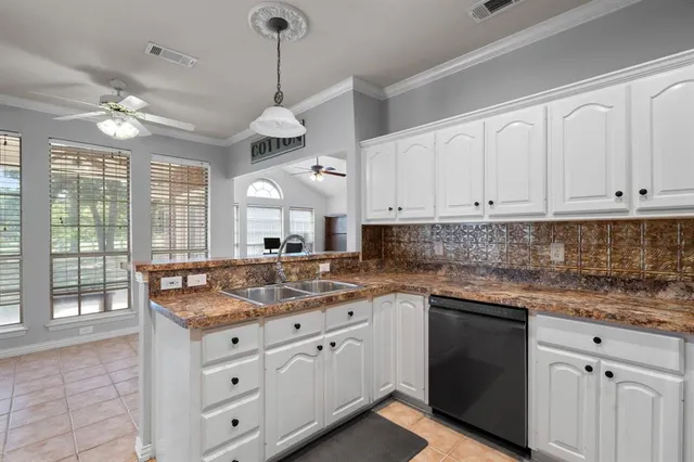 a kitchen with granite countertop white cabinets white appliances a sink and a window